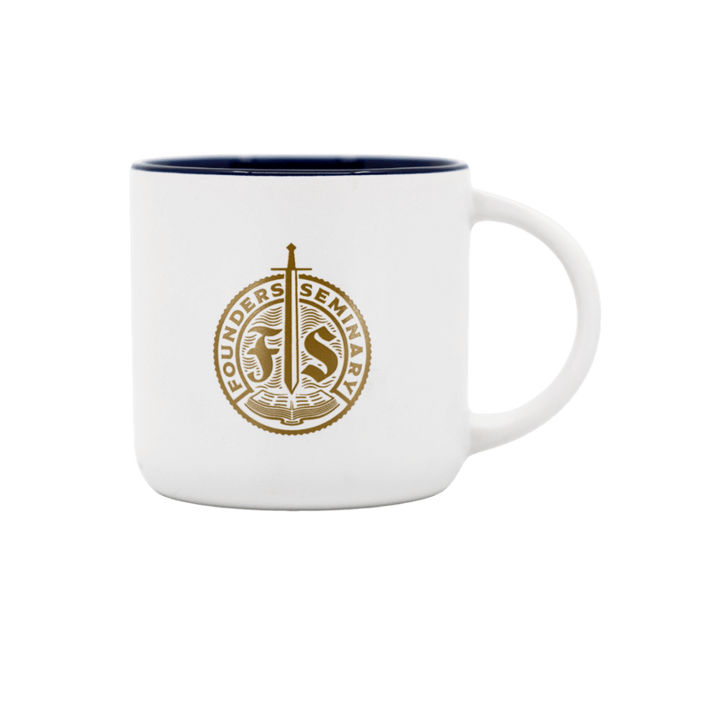 A white ceramic coffee mug with a dark navy blue interior rim and handle, featuring a gold circular seal for Founders Seminary printed on the front.