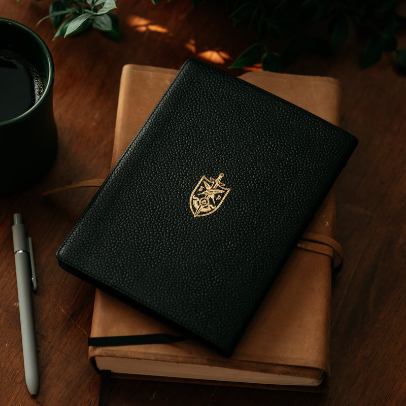 Back of leather 1689 with Founders Press logo on table with cup, pen, and plant. 