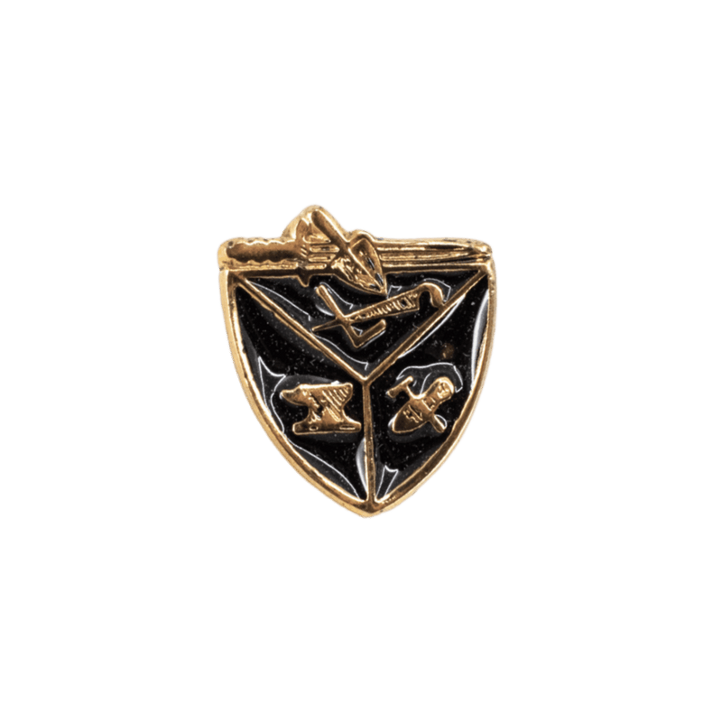 A small shield-shaped metal pin or badge with a gold-tone border and black enamel fill, featuring crossed tools and a central emblem, shown on a plain white background.