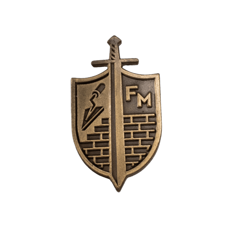 A bronze-colored metal shield and sword emblem pin with the letters 'FM' on the right side, isolated on a white background. [Gold]
