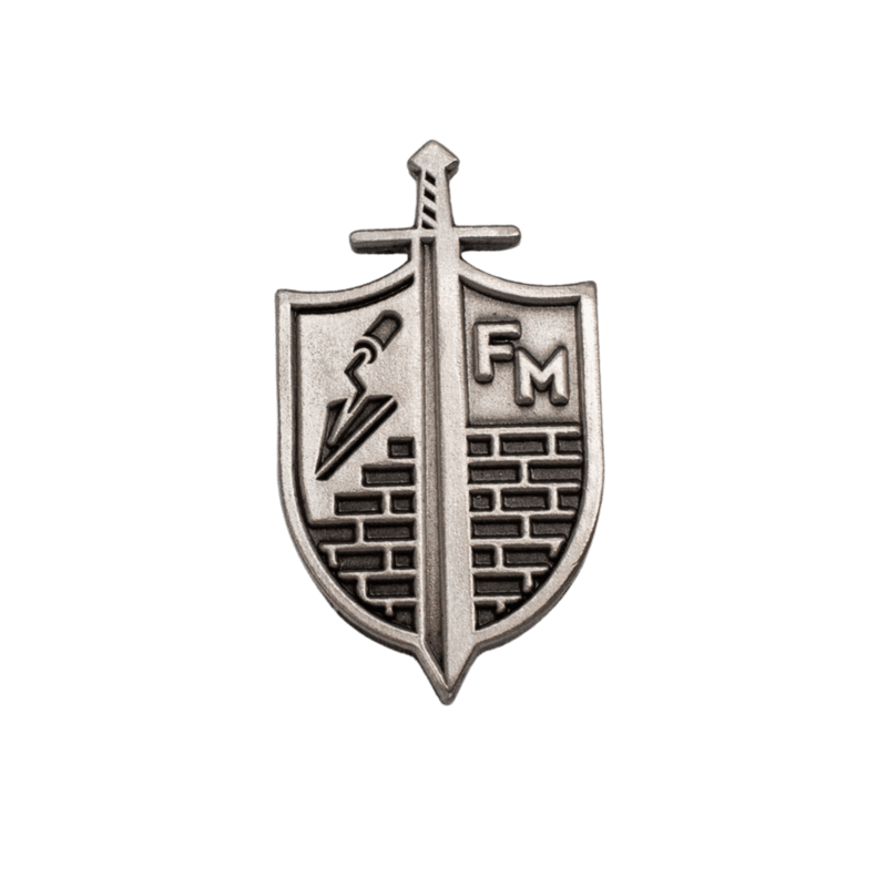 A silver-toned metal crest pin shaped like a shield, featuring a vertical sword down the center, brick patterns on the lower half, and the letters 'FM' on the right, shown on a plain white background. [Silver]