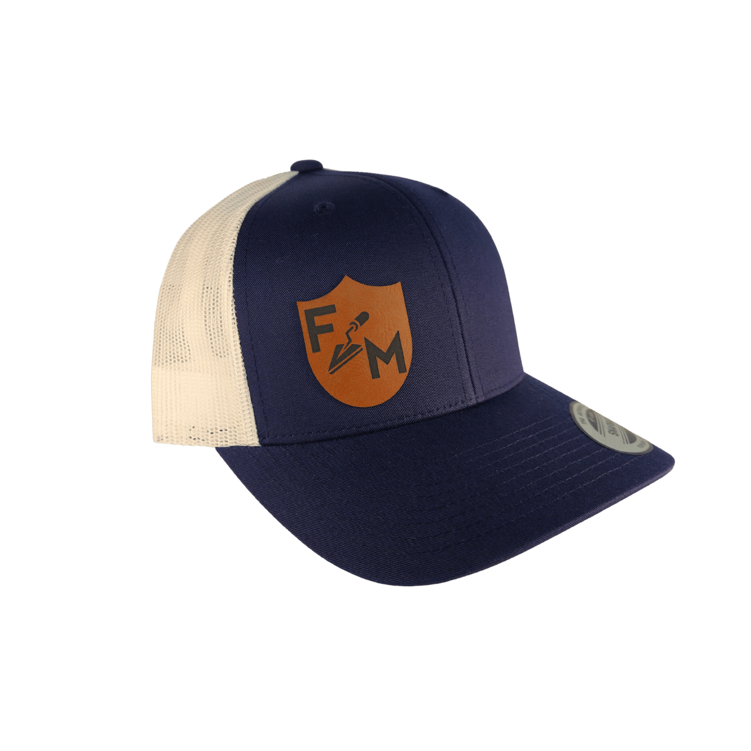A navy blue and cream trucker hat with a brown shield logo on the front, shown against a solid green background.