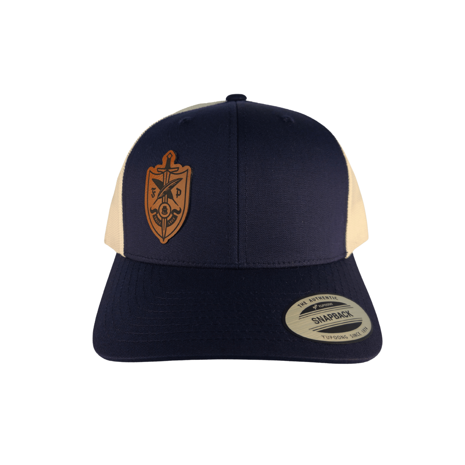 A structured trucker-style cap with a navy blue front and brim, cream mesh side panels, and a tan shield emblem on the front. 