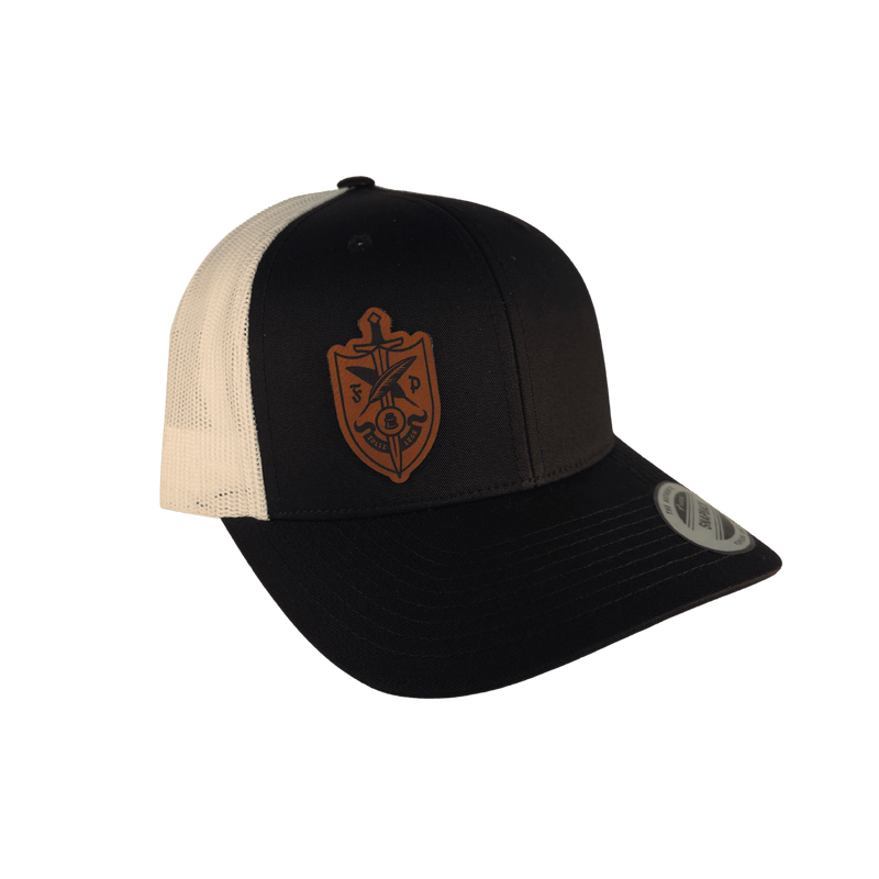 A black and cream trucker cap with a brown shield logo on the front.