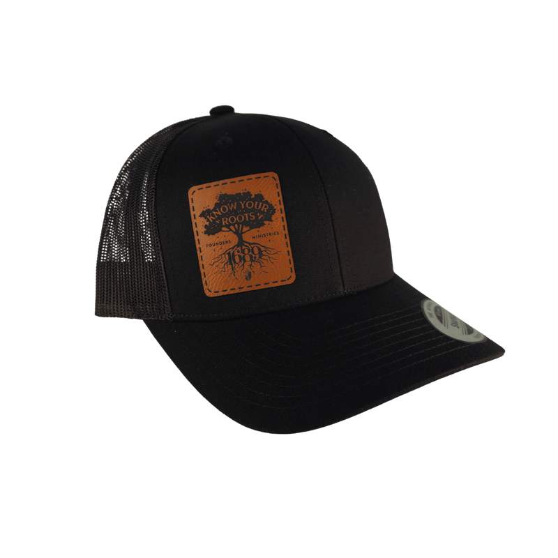 A black trucker hat with a brown leather patch on the front displaying 'Know Your Roots 1689' and a tree graphic.