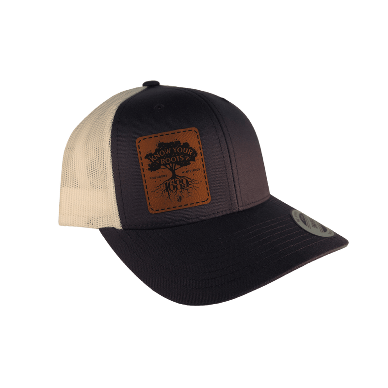 A grey trucker hat with a brown leather patch on the front displaying 'Know Your Roots 1689' and a tree graphic.