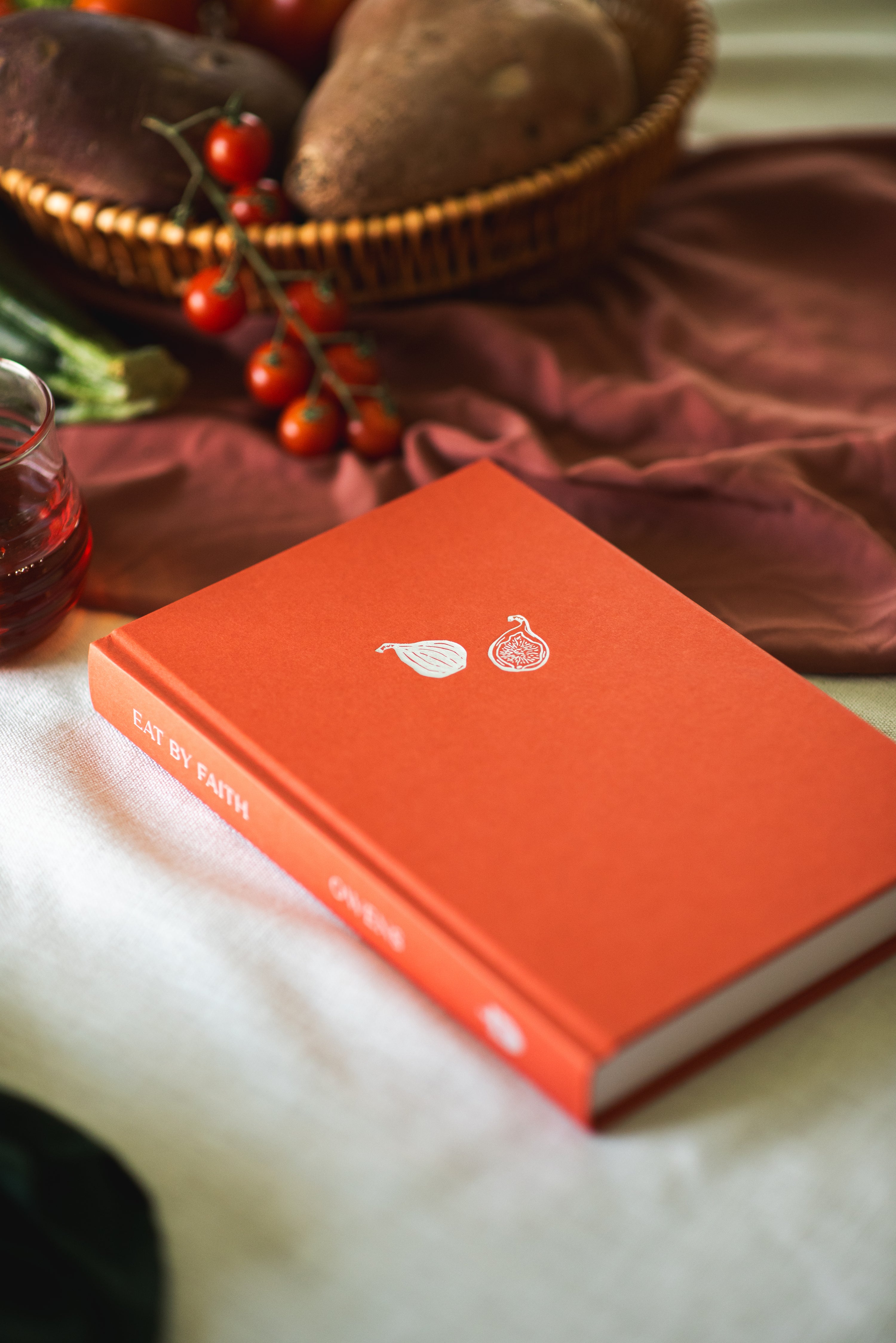 Book titled Eat by Faith by Kat Owens staged on a table with various food items. 