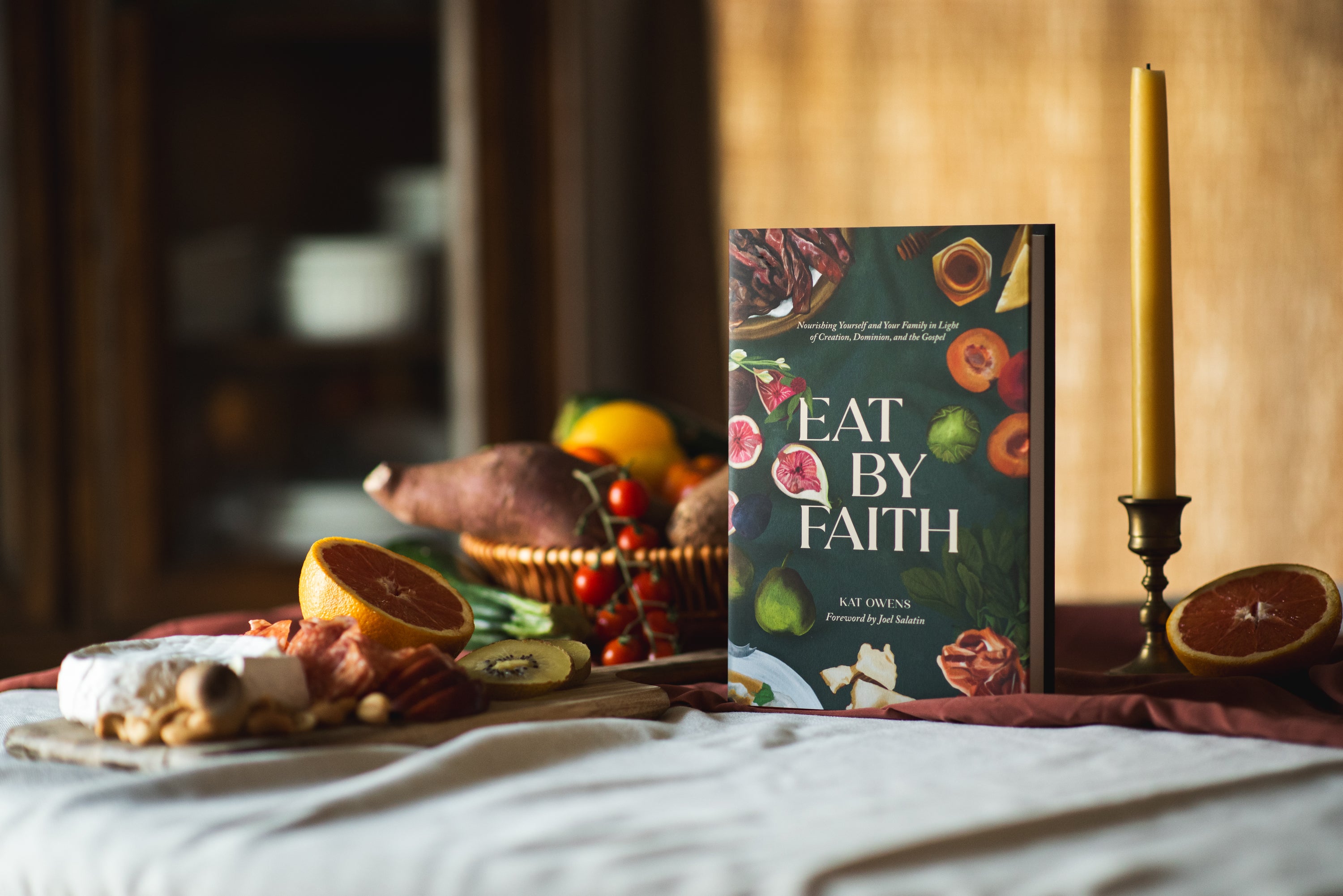 Book titled Eat by Faith by Kat Owens staged on a table with various food items. 