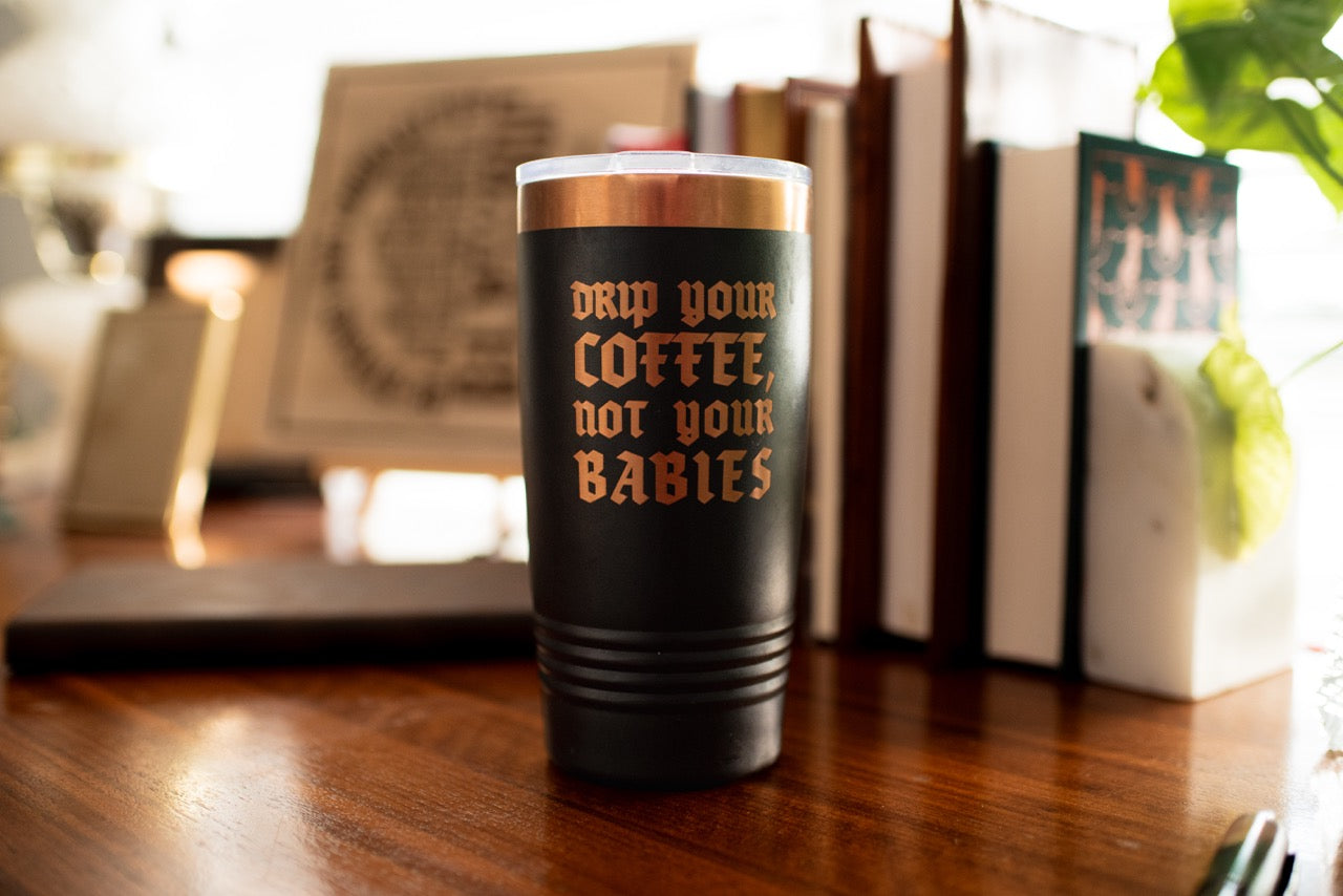 Drip Your Coffee, Not Your Babies Tumbler on wood table with books in background