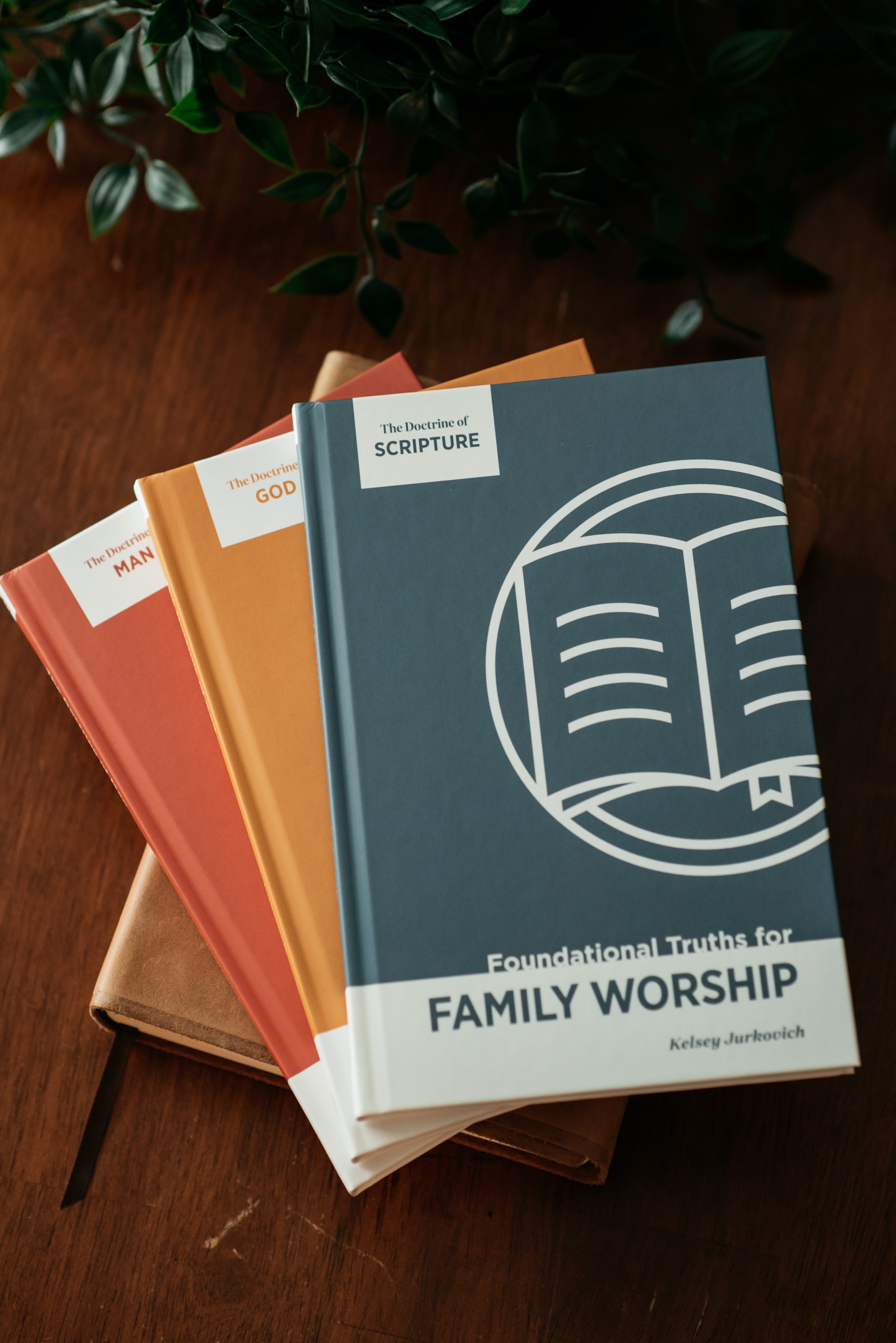 Stack of Family Worship Guides on a wooden surface with a plant in the background