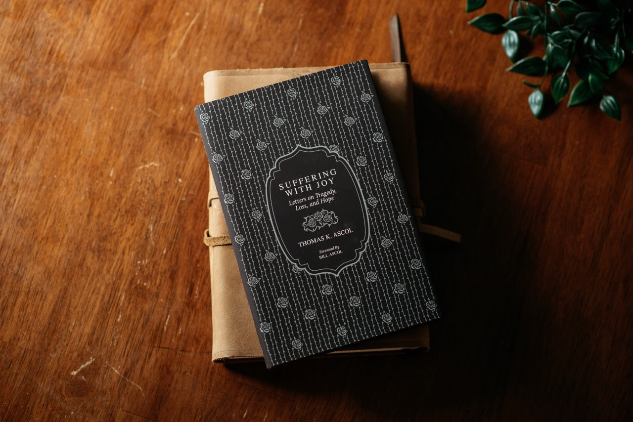 Suffering with Joy Book on Wood table with plant