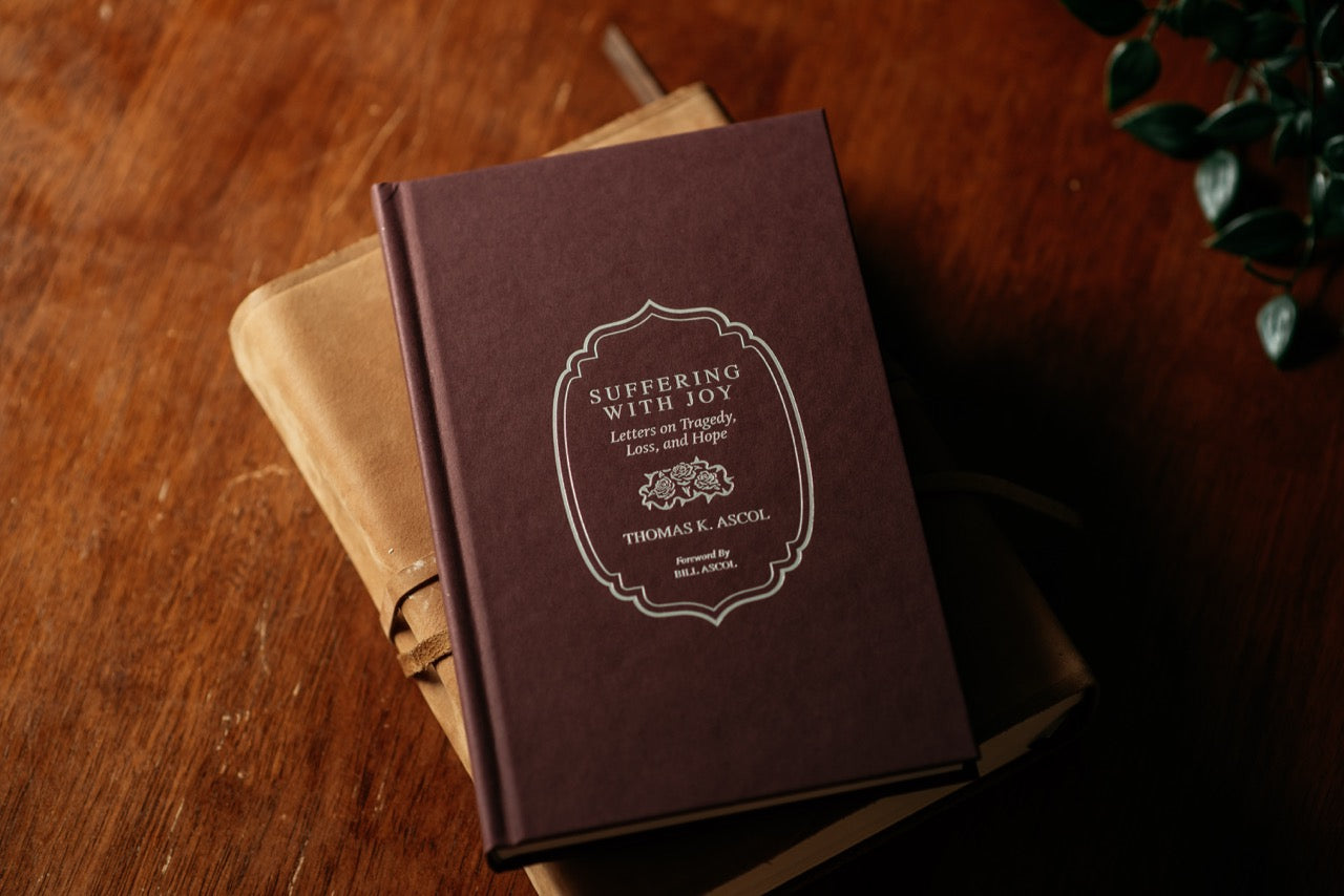 Suffering with Joy Book on Wood table with plant