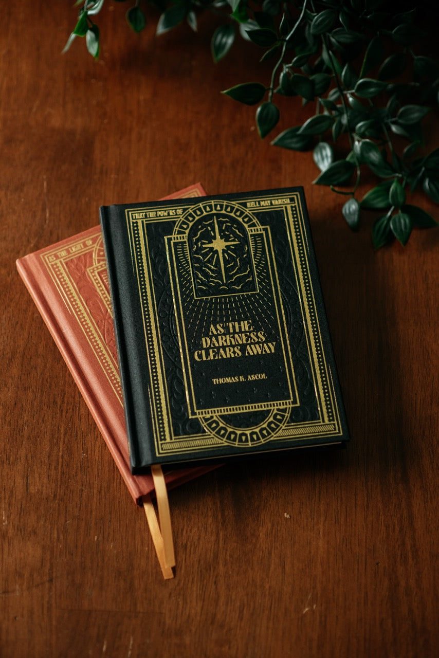 As the Darkness Clears Away book on wooden table with plant. 