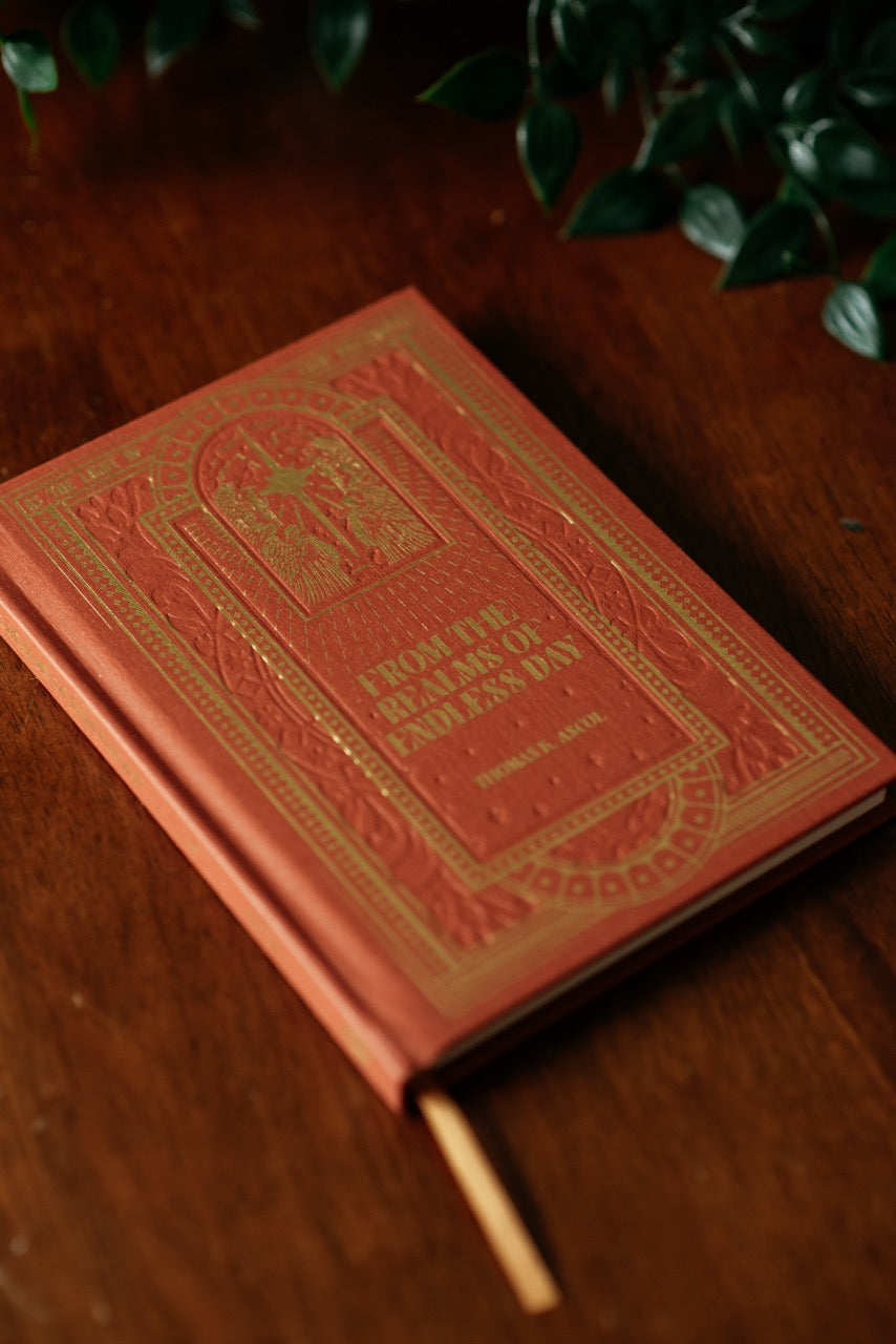  From the Realms of Endless Day books on wooden table with plant. 