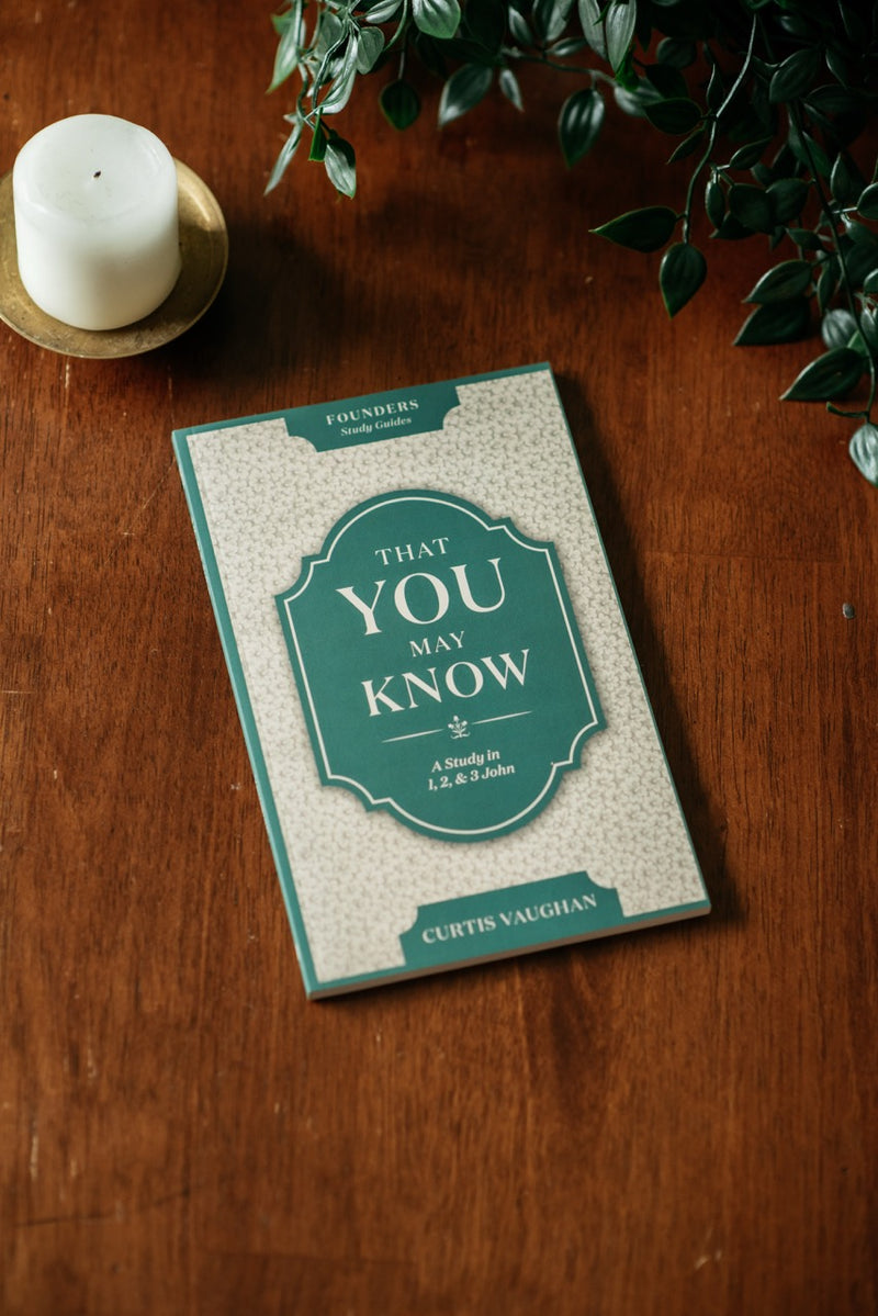 That You May Know Book on wood table with plant and candle. 