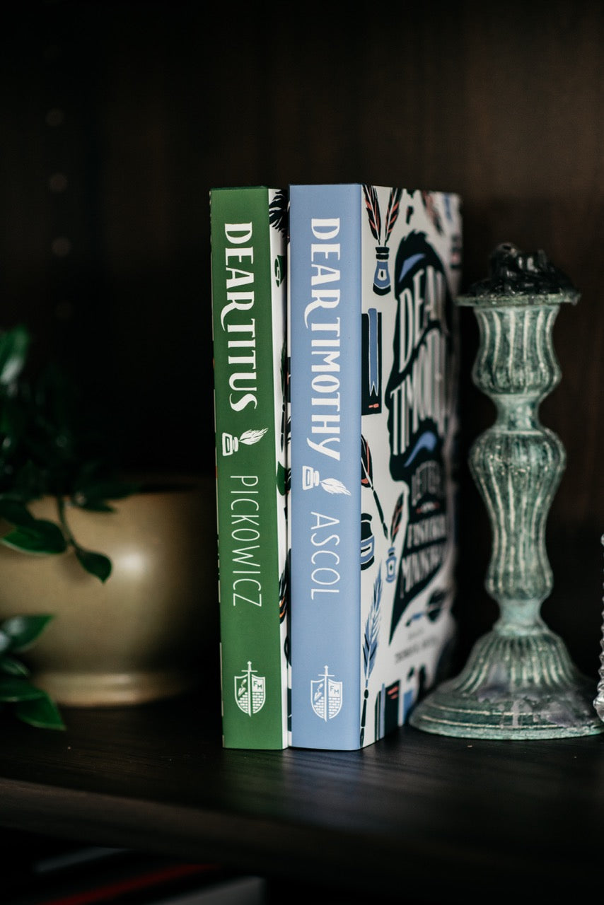 Dear Timothy and Dear Titusbooks on wood shelf with plant and decorative elements. 