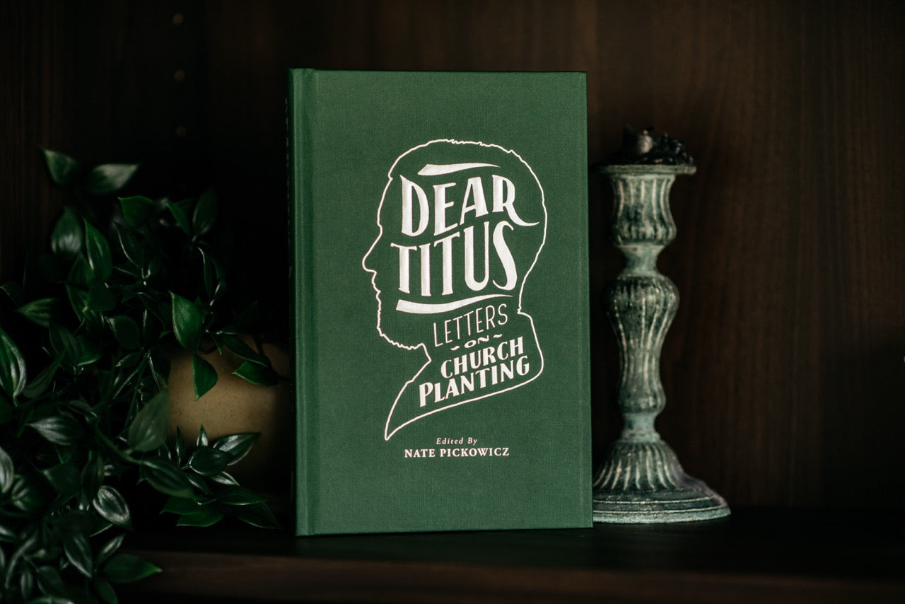Dear Titus book on wood shelf with plant and decorative elements. 