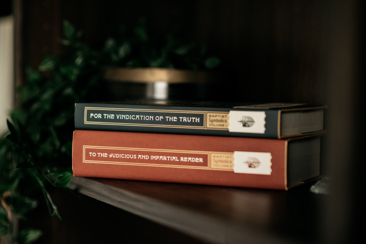 Baptist Symbolics book series on wood table with plant [English]