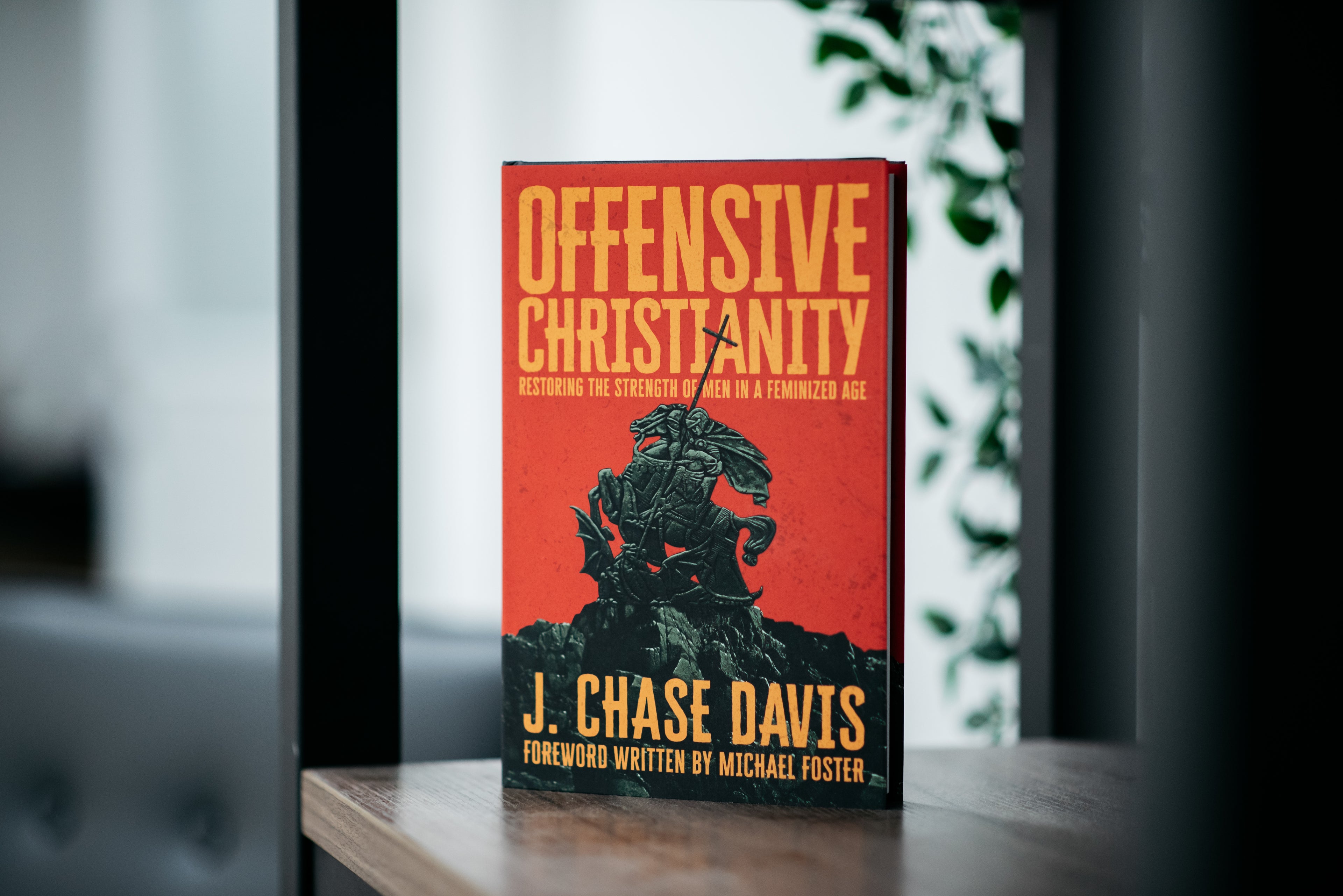 Book titled 'Offensive Christianity' by J. Chase Davis on a wooden surface with a blurred background