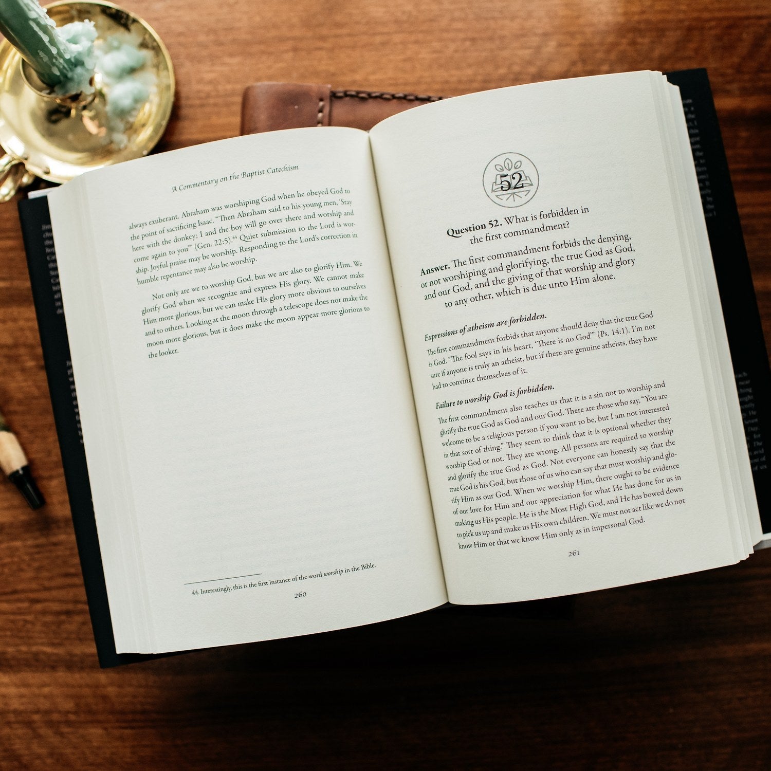 Open book on a wooden surface with a candle in the background