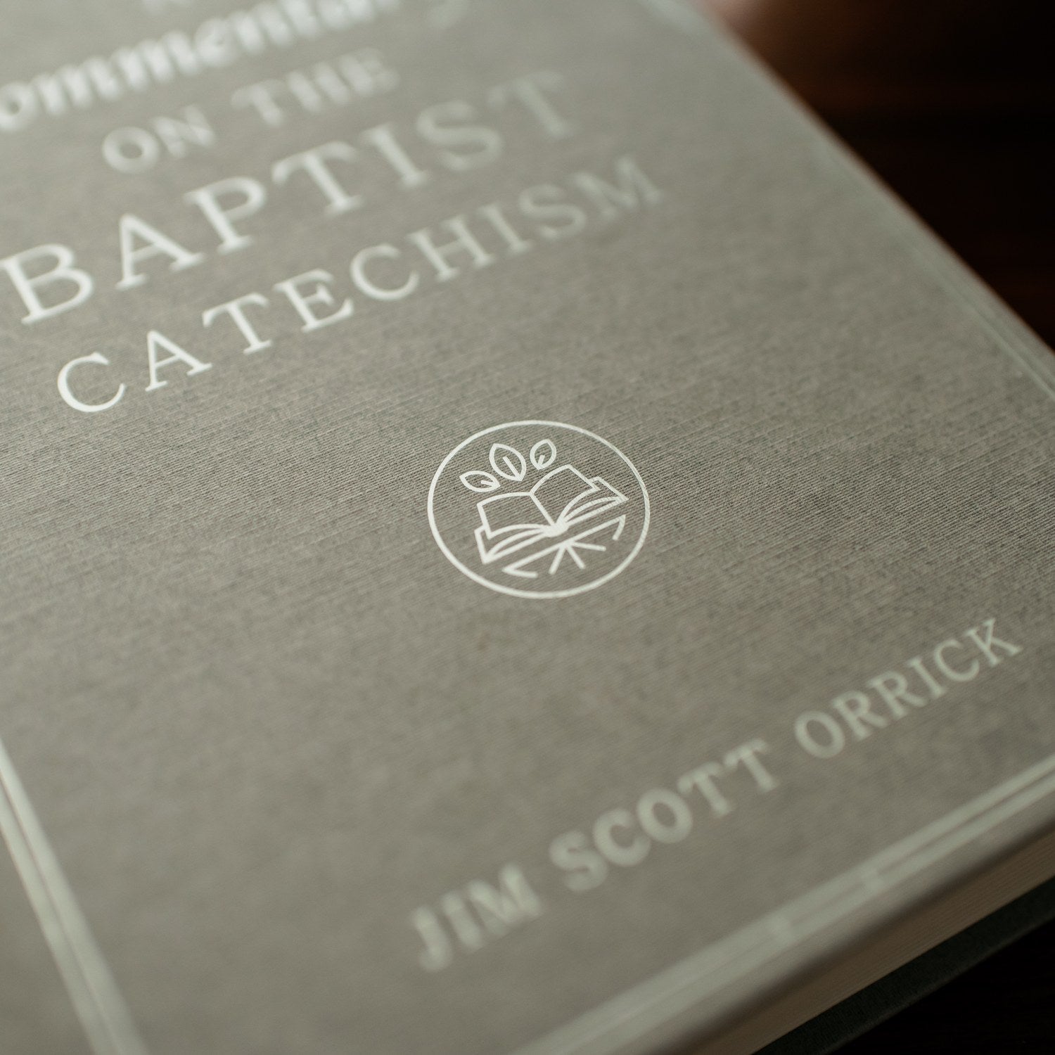 Book titled 'Commentary on the Baptist Catechism' by Jim Scott Orrick with a logo on a gray background.