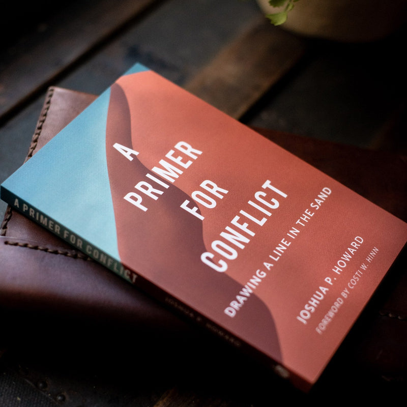 Book titled 'A Primer for Conflict' on a wooden surface
