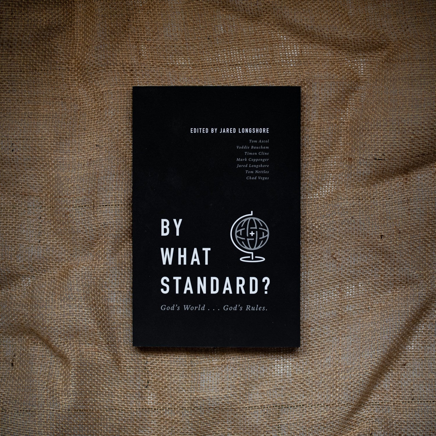 Black book titled 'By What Standard?' on a textured brown surface