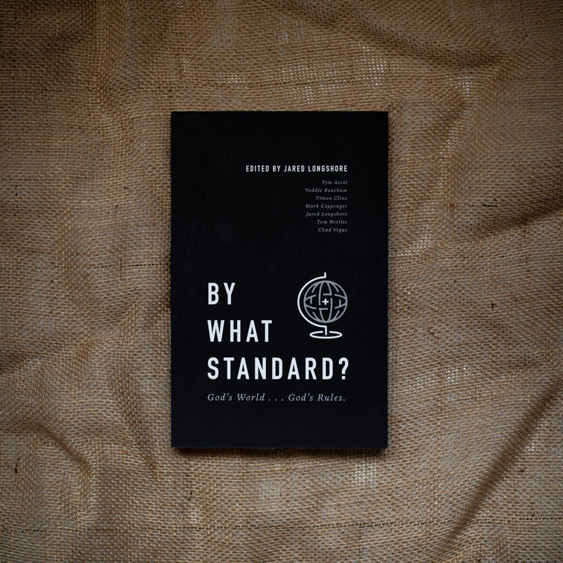 Black book titled 'By What Standard?' on a textured brown surface