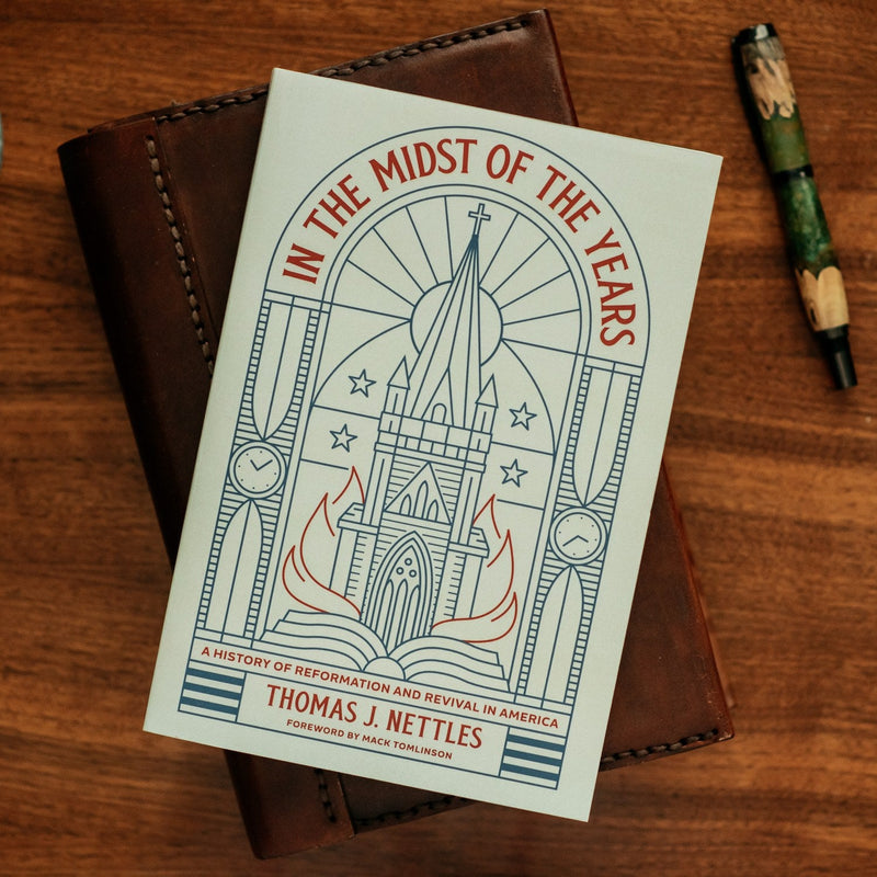 Book titled 'In the Midst of the Years' by Thomas J. Nettles on a wooden surface with a pen.