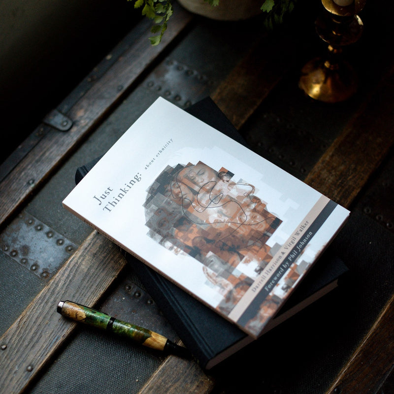 Book titled 'Just Thinking' on a wooden surface with a pen and decorative items.