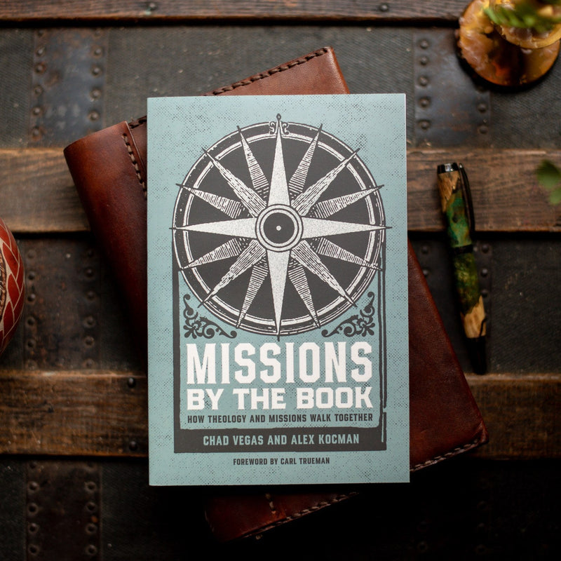 Book titled 'Missions by the Book' with a compass design on a wooden surface.