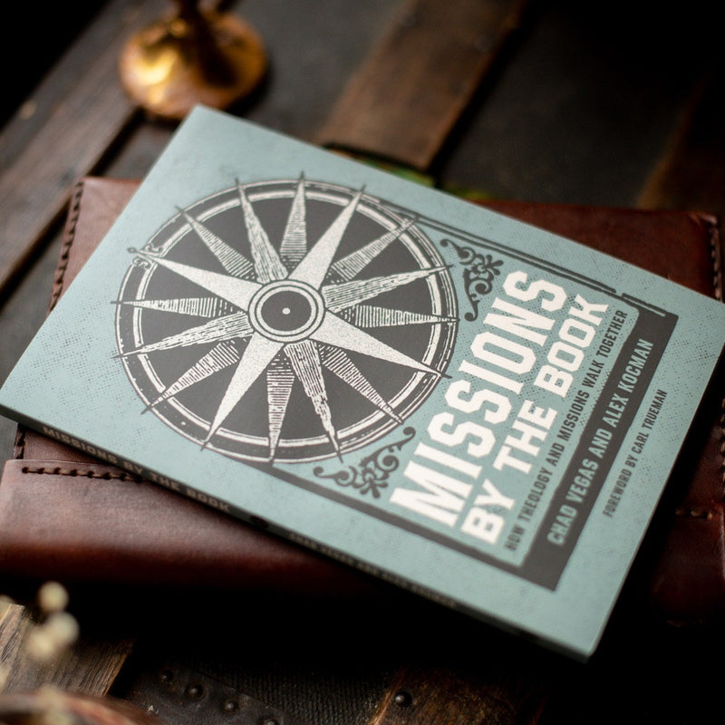 Book titled 'Missions by the Book' with a compass design on a wooden surface