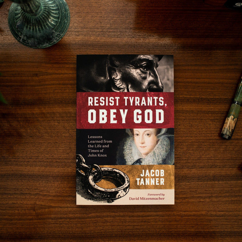 Book titled 'Resist Tyrants, Obey God' by Jacob Tanner on a wooden surface.