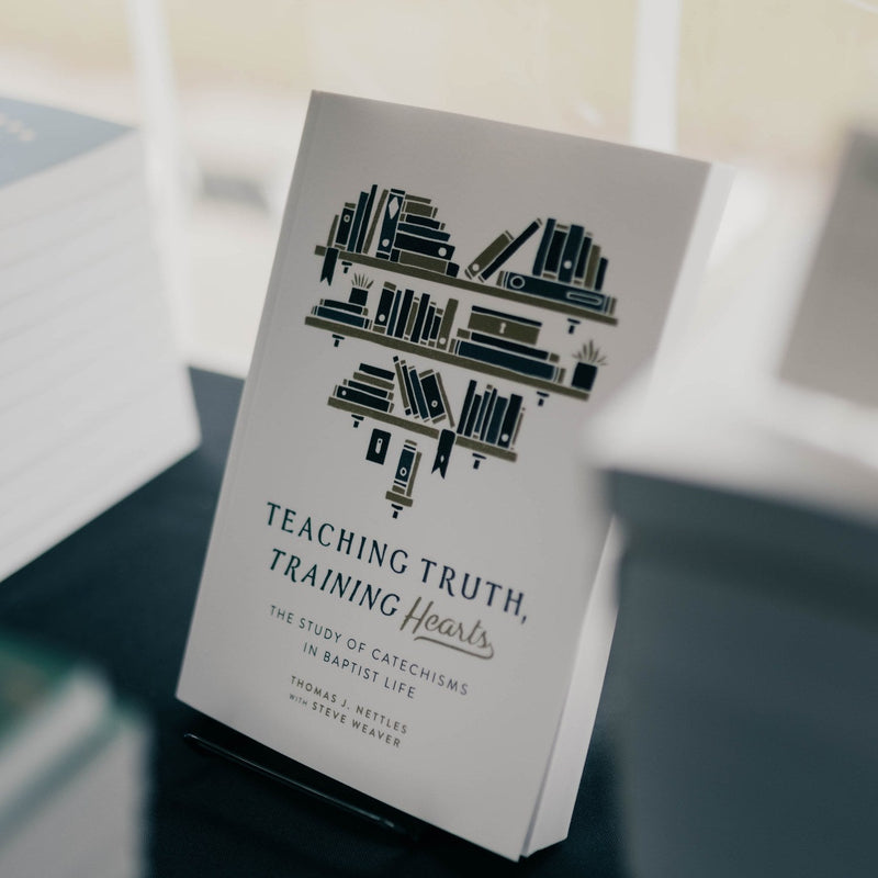 Book titled 'Teaching Truth, Training Hearts' on a stand with blurred background