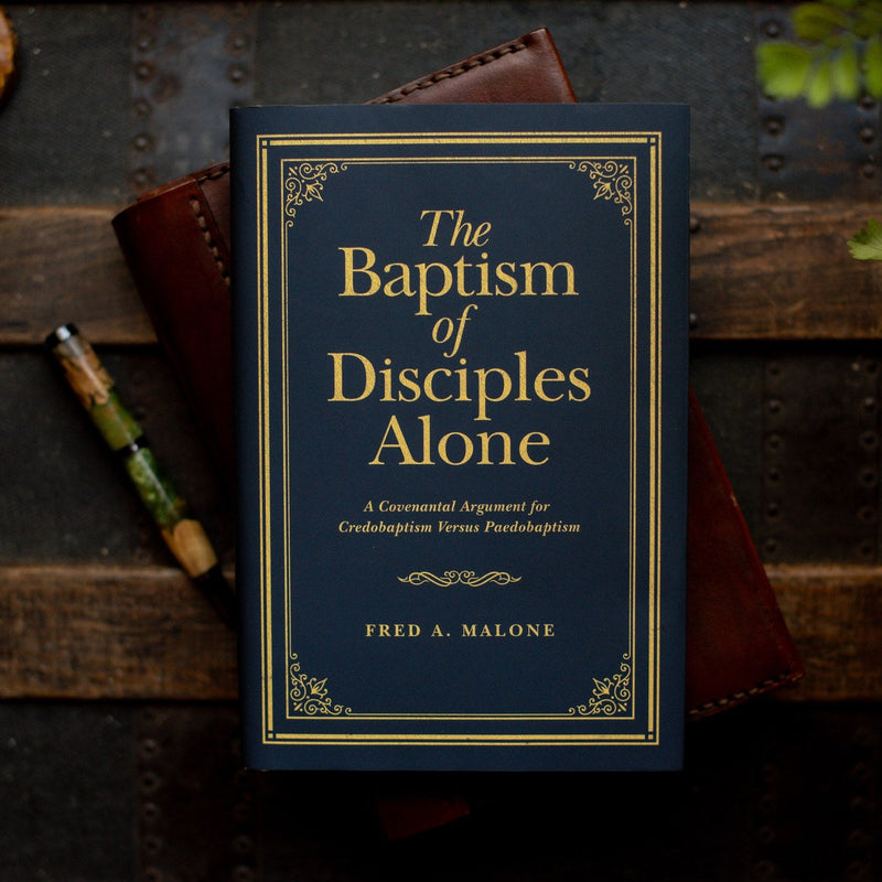 Book titled 'The Baptism of Disciples Alone' by Fred A. Malone on a wooden surface. [English]