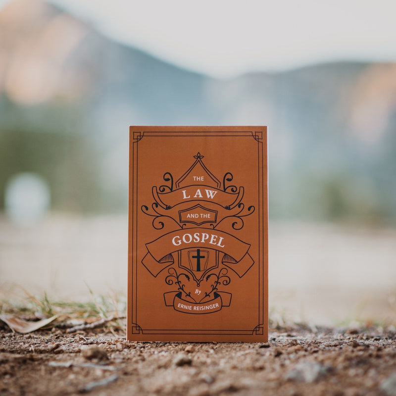Brown book titled 'The Law and the Gospel' by Ernie Reisinger on a natural background