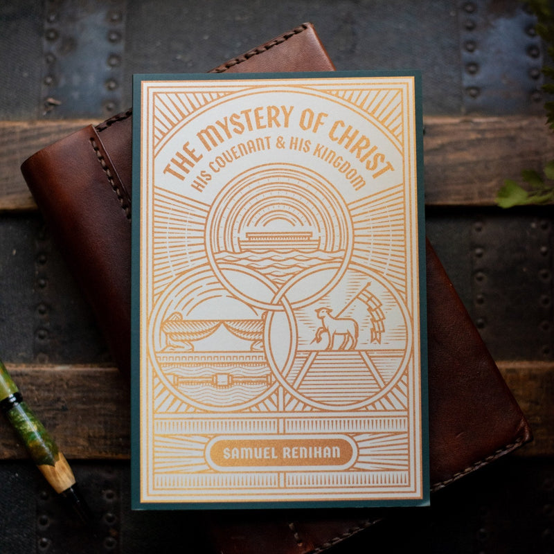Book titled 'The Mystery of Christ' by Samuel Redihan on a wooden surface with a leather-bound book.