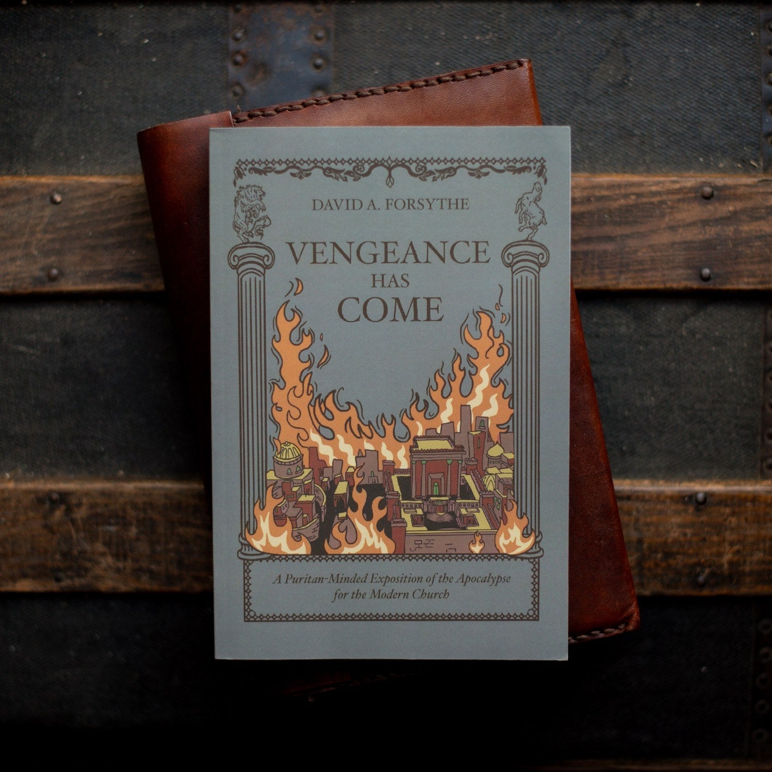 Book titled 'Vengeance Has Come' by David A. Forsythe with a leather-bound book in the background.